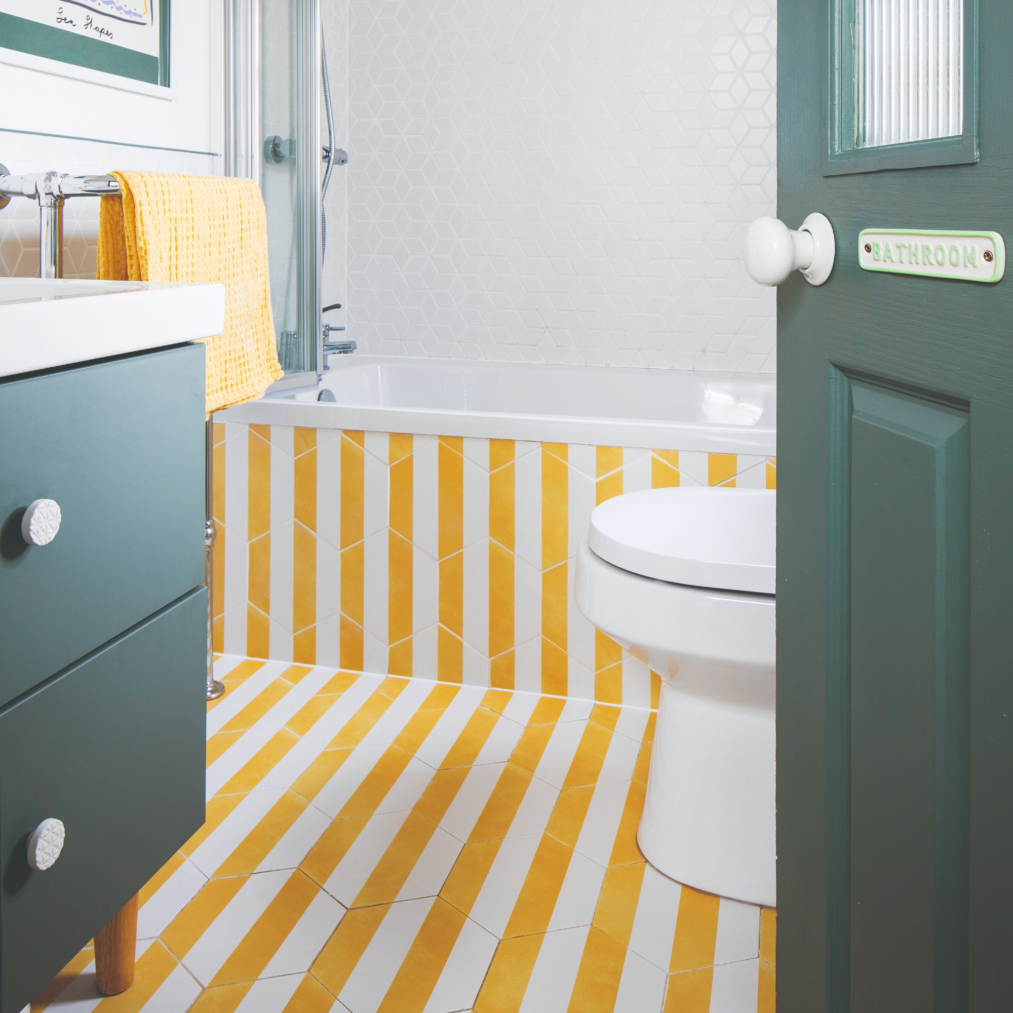 A bathroom with the floor and bathtub covered in hexagonal striped tiles in yellow and white