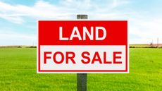 A Land For Sale sign on a vacant lot.