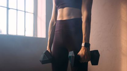 A woman doing dumbbell arm workouts at the gym