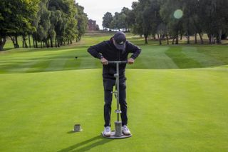 Dan Parker cutting a hole into a green at Edgbaston golf club