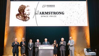 eight men and women in evening wear stand together on stage under a large white sign for Purdue University's Neil Armstrong Space Prize