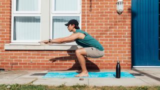Man performs unweighted squat exercise outdoors