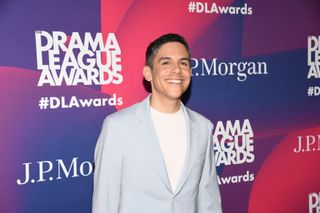 Matthew López posing for photographers in front of a branded backboard at the Drama League Awards