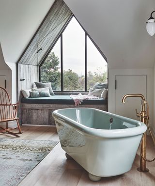 Large bathroom with white bath, copper tap, vaulted window seat, wooden flooring