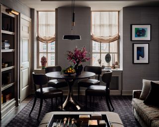 gray family room with dark round table and chairs, pendant light, bookcase, patterned rug and sofa