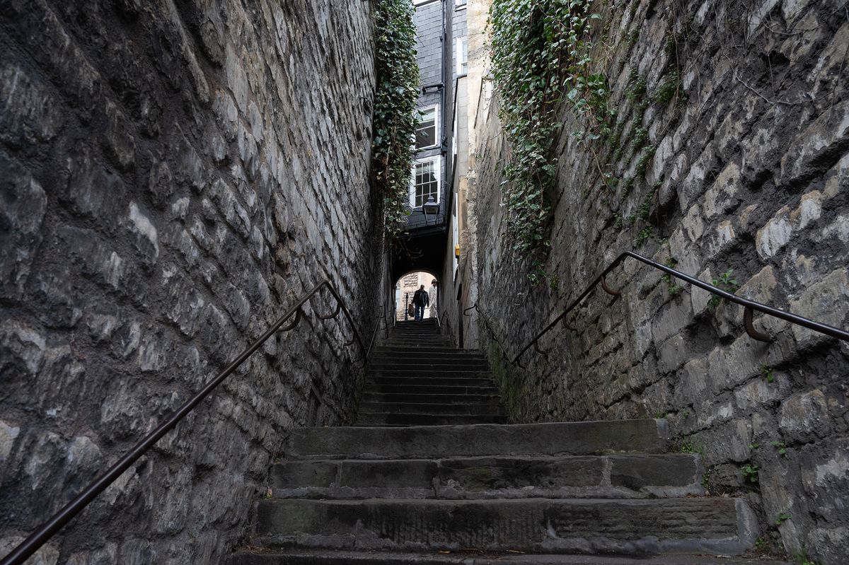 A silhouetted figure descending an avenue of stone steps