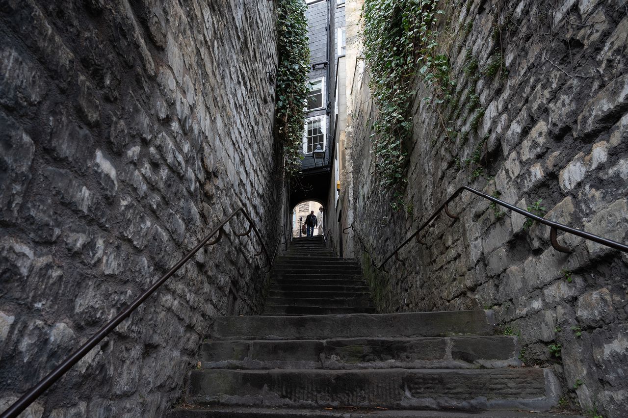 A silhouetted figure descending an avenue of stone steps