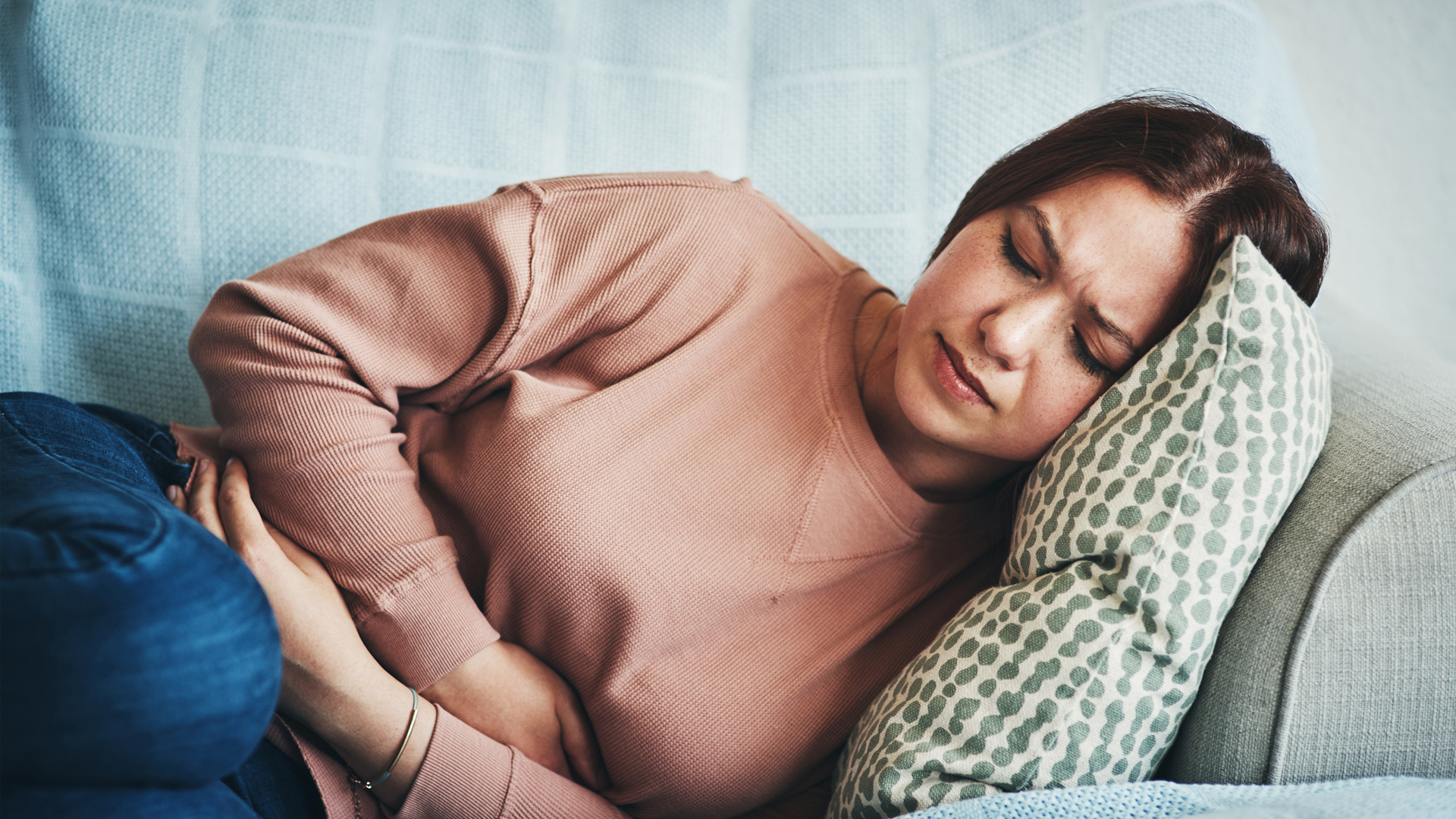 mujer sosteniendo su estómago con dolor