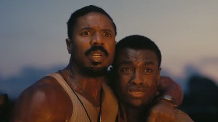 Michael B. Jordan with arm around Miles Caton, both looking frightened at an unknown sight in Sinners