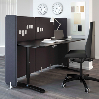 A home office setup with wooden desk and office chair and makeshift cubicle using wall divider