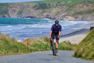 A male cyclist climbing a hill on the Welsh coast