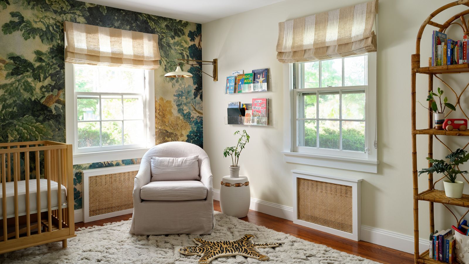 neutral nursery bedroom with a tapestry style wall mural, beige and white striped window blinds, wooden cot and neutral arm chair