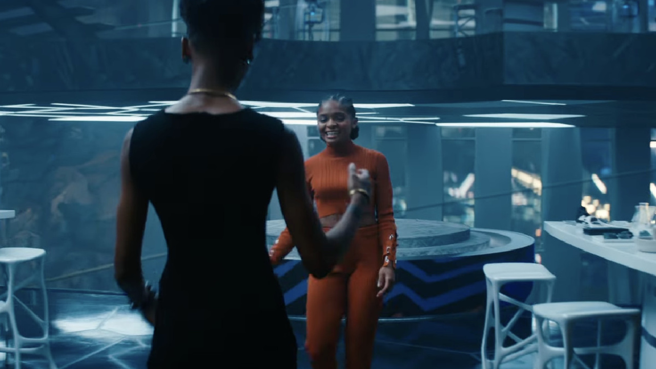 Iron Hart (orange) and Shuri talk in Black Panther: Wakanda Forever.