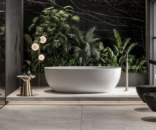 A luxury bathtub in white in a bathroom with greenery in