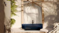 An outdoor bathroom with a blue freestanding bathtub, an oversized woven light fixture, and a separate shower area