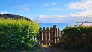Gardening twice a week helps relieve stress, new study shows: An image of a garden gate overlooking a golden beach