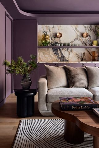 a purple living room with a marble wet bar in the background and a grey sofa