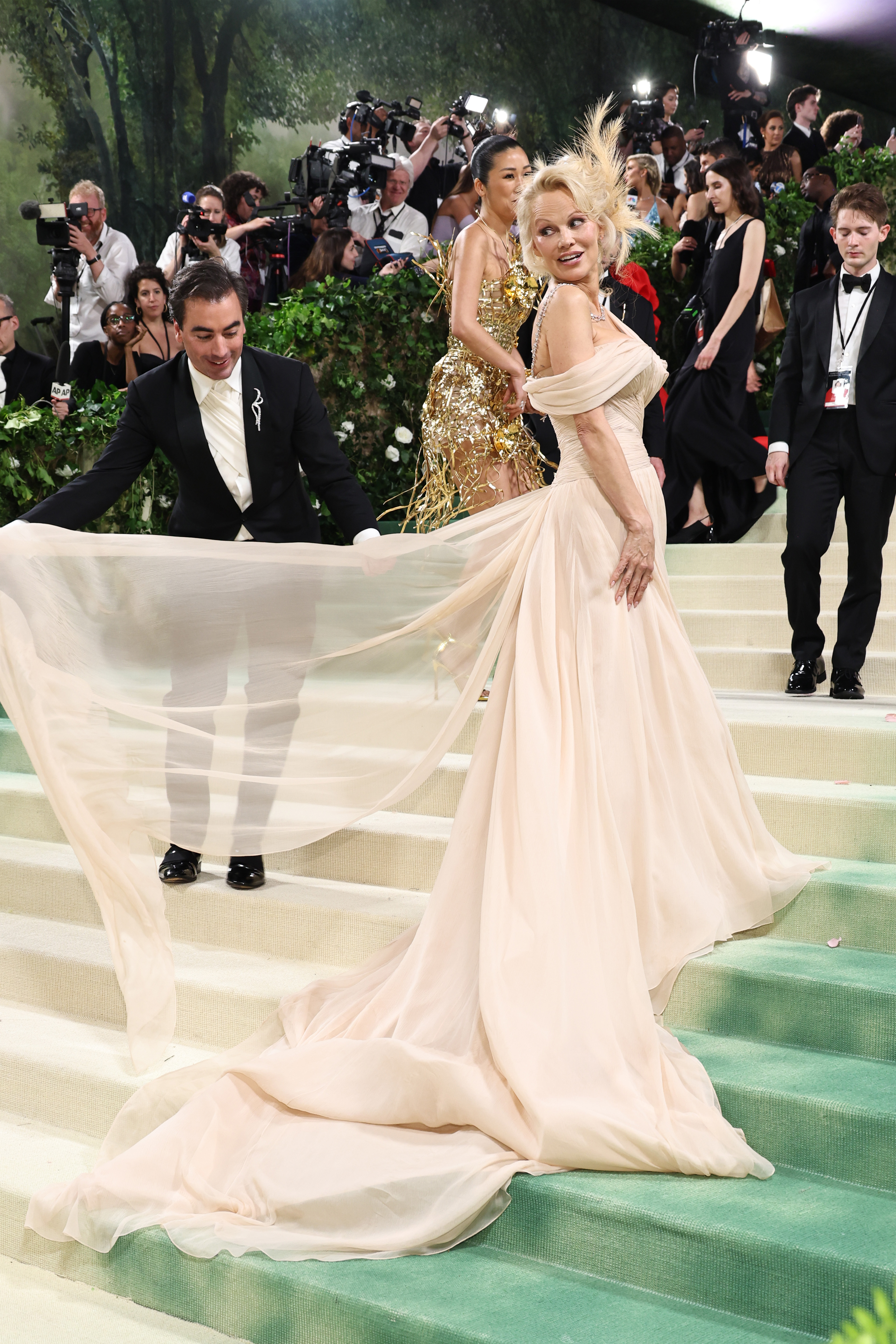 Pamela Anderson looks over her shoulder at the 2024 Met Gala wearing a nude colored gown