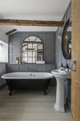 square gray paneling in bathroom with rolltop bath and window