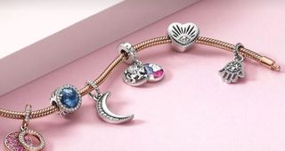 Image of a Pandora charm bracelet with lots of charms on, on a pink background