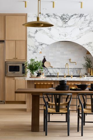 a wood and marble kitchen with an arched hood