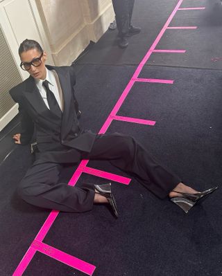 Bella Hadid wearing a Saint Laurent suit and tie backstage at the S/S 25 runway show.