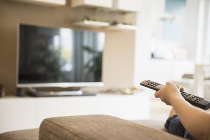 Woman watching TV with remote control in her hand