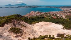 A view of the Solfatara crater in Italy's Campi Flegrei volcano caldera with the Mediterranean Sea in the background.