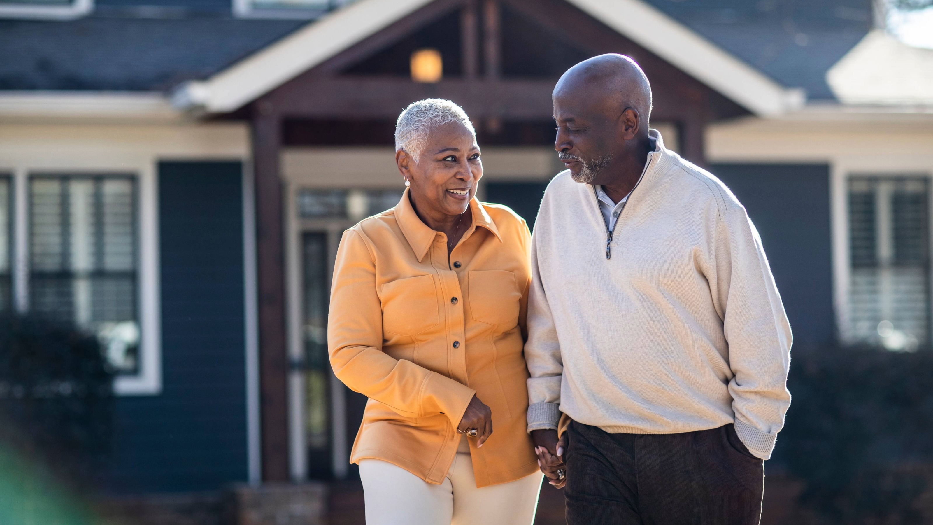 Happy senior couple couple walking in front of their home