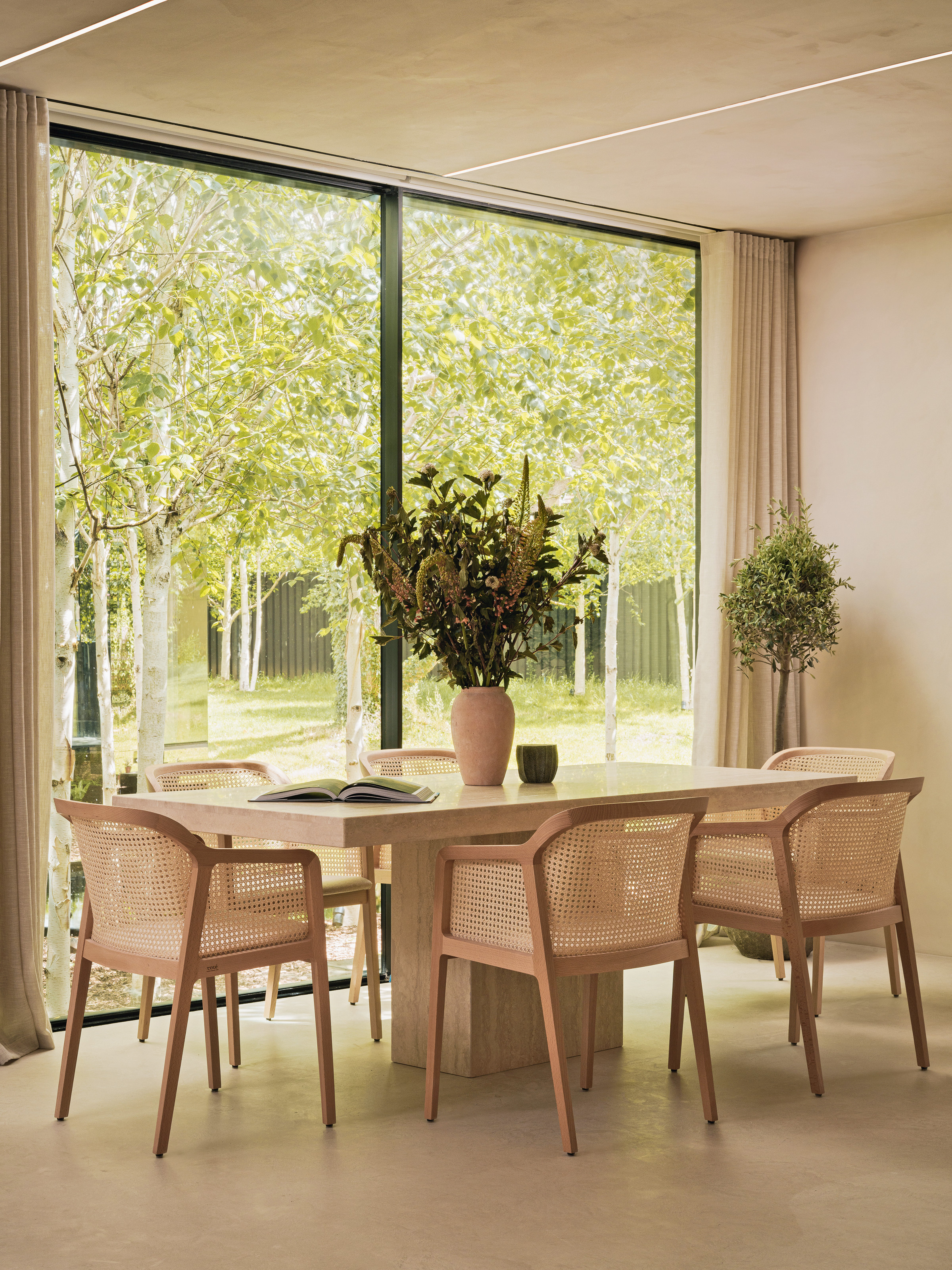 Dining table with rectangular pedestal table, cane chairs and large flower arrangement