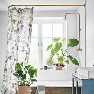 White bathroom with floral shower curtain and brass fixtures