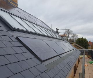 Solar panels on a pitched roof under a row of roof glazing