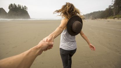 woman on beach holding partner's hand - women financial literacy