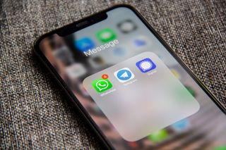 A smartphone on a sofa showing the WhatsApp, Telegram and Signal apps