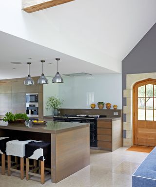neutral kitchen with wooden cabinets, cown hide stools and metal pendant lights