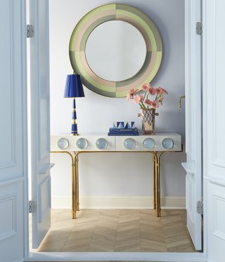 pastel blue hallway/entryway with retro sideboard, large sound mirror, blue lamp and wooden flooring