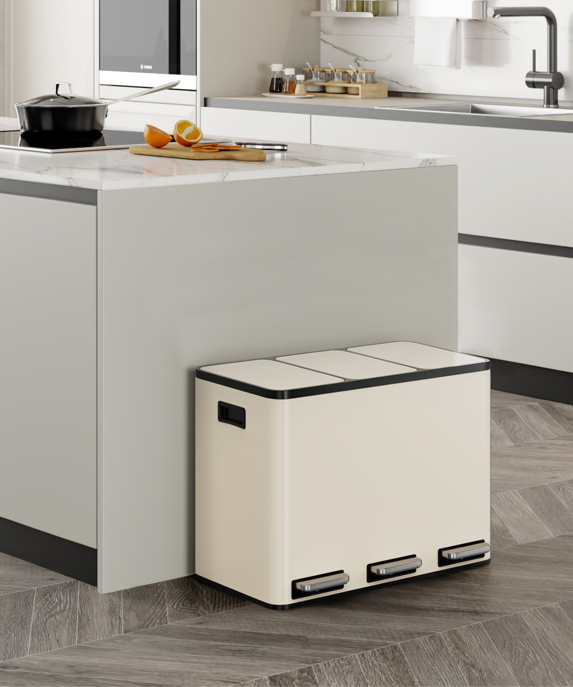 A cream-coloured kitchen recycling bin with three pedal-operated compartments, designed for separating waste, positioned neatly against a kitchen island.