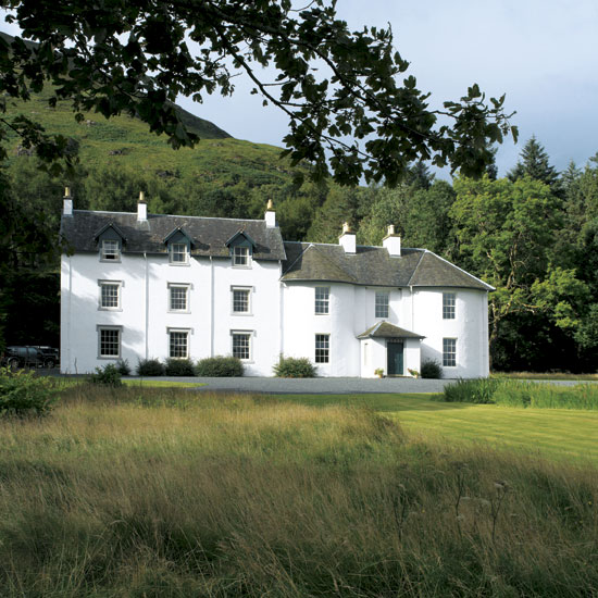 white cottage with grey roof trees and grass