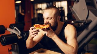 A man eating pizza at the gym