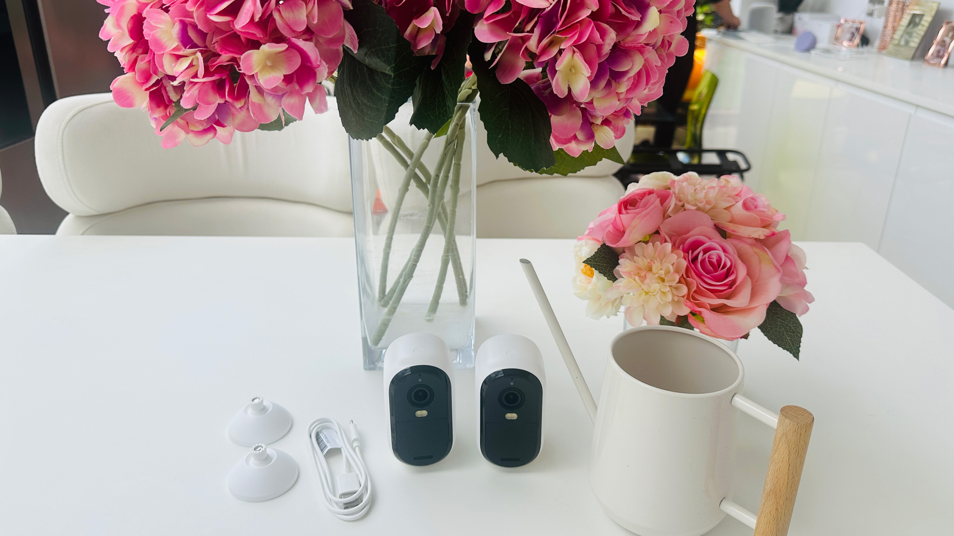 2 Arlo Essential 2nd generation cameras on the kitchen counter after unboxing next to flowers and a mug