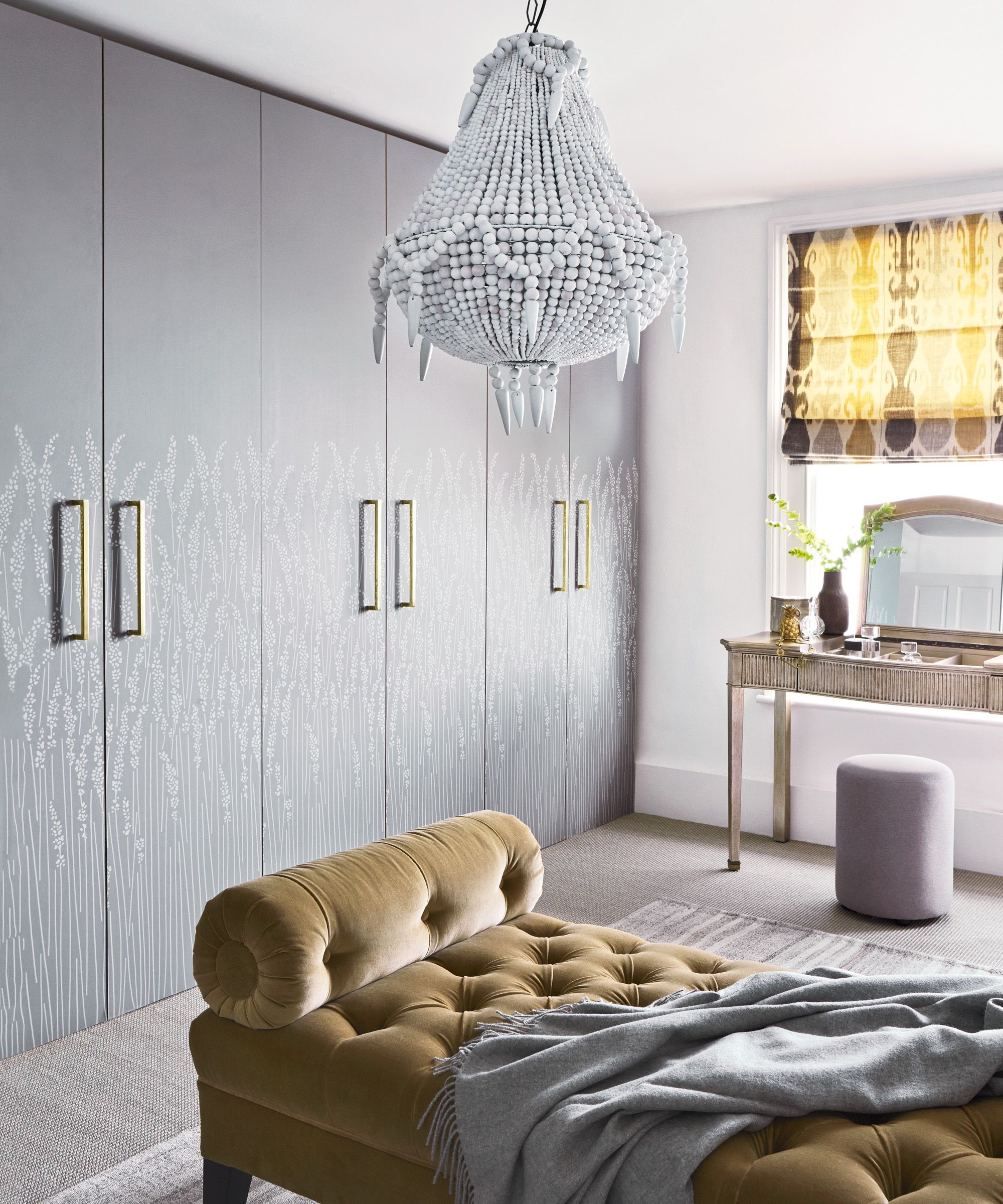 A bedroom with an empire-style chandelier and gold velvet daybed