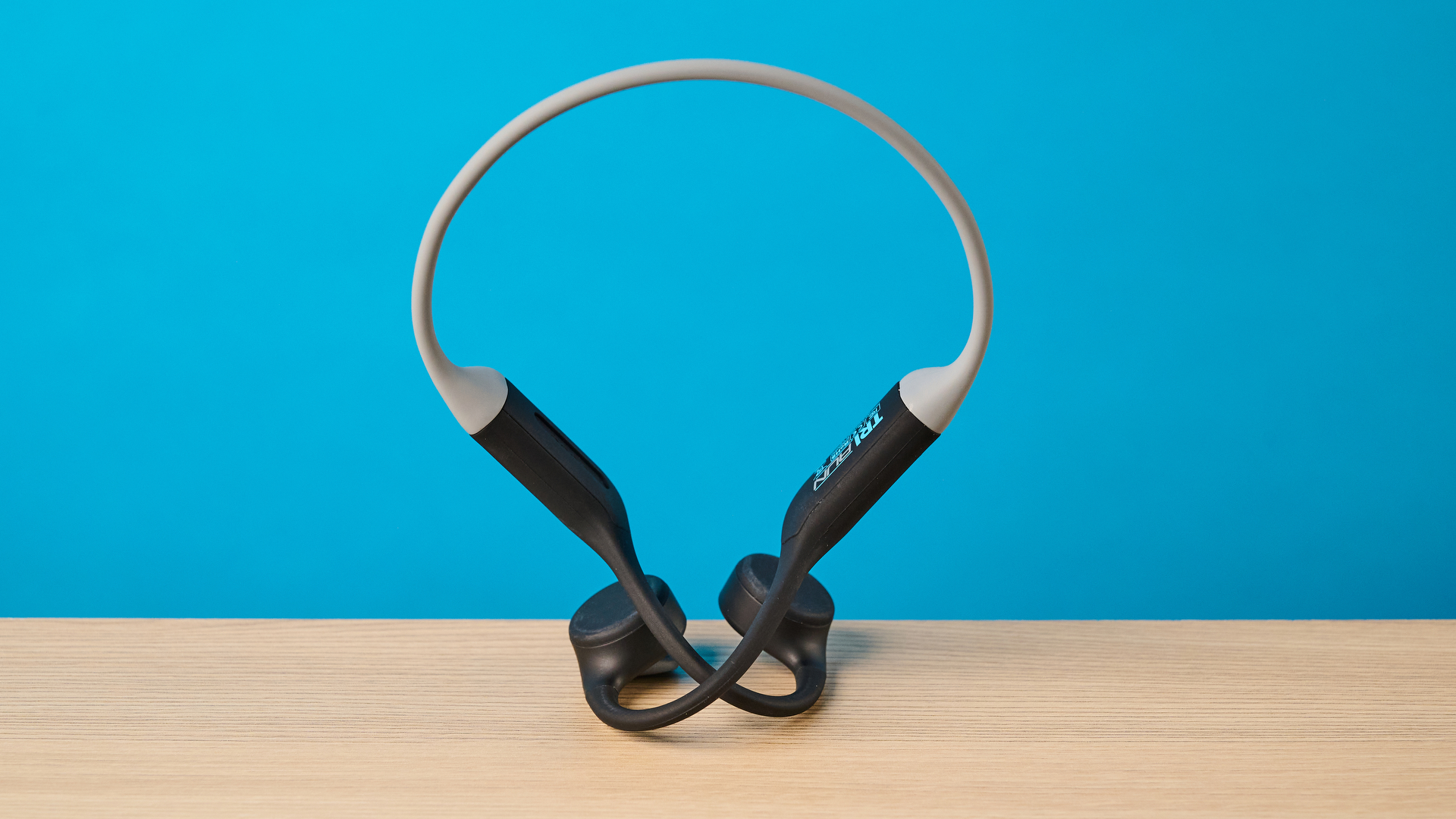 the h2o audio tri run bone conduction headphones photographed against a tom's guide blue background