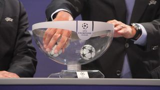 Suited man picks mini football out of Champions League draw bowl