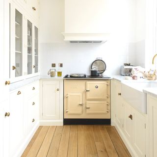 white galley kitchen with blonde wood floor and cream range cooker