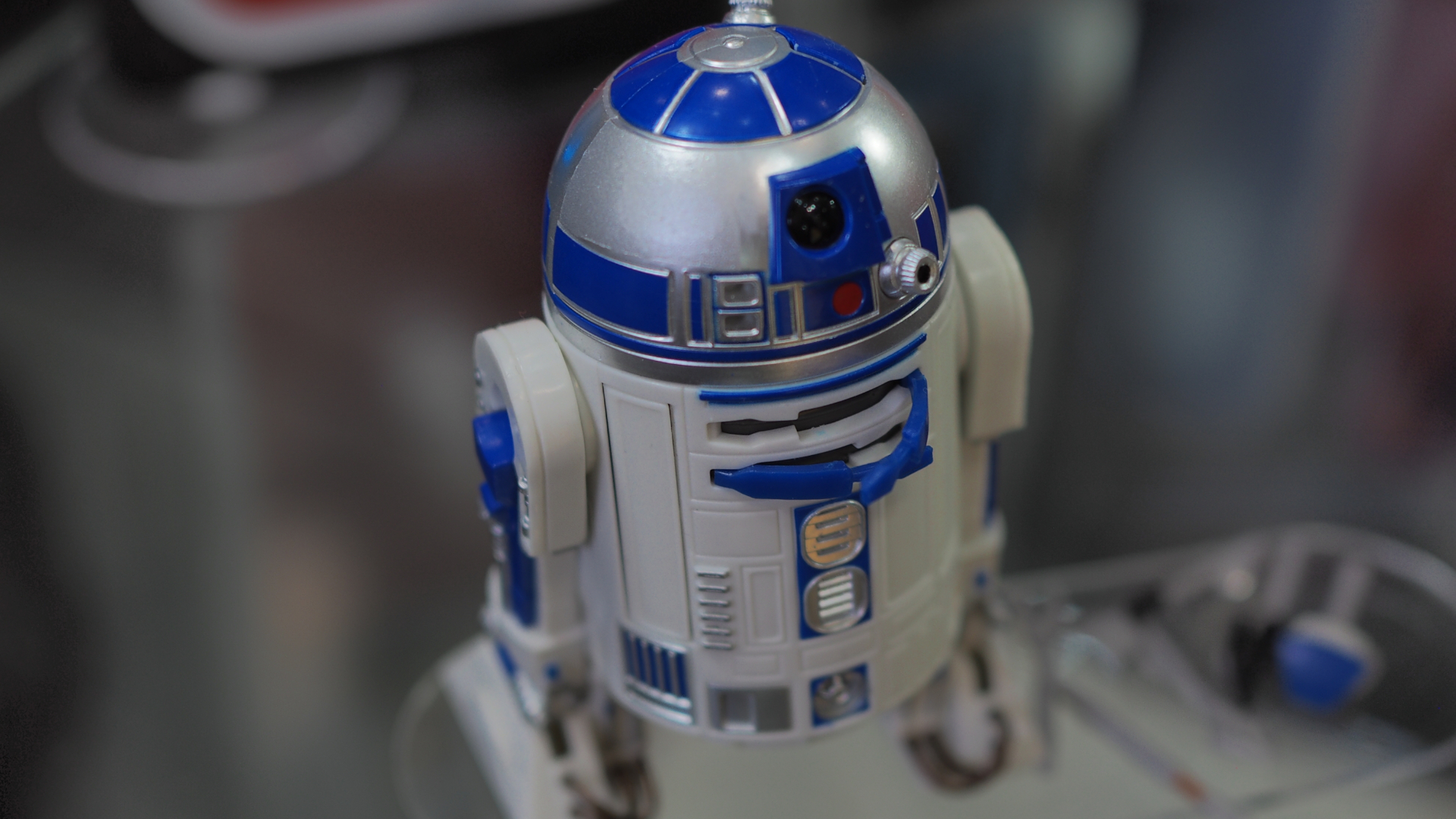 An action figure of R2-D2 stands with certain accessories out