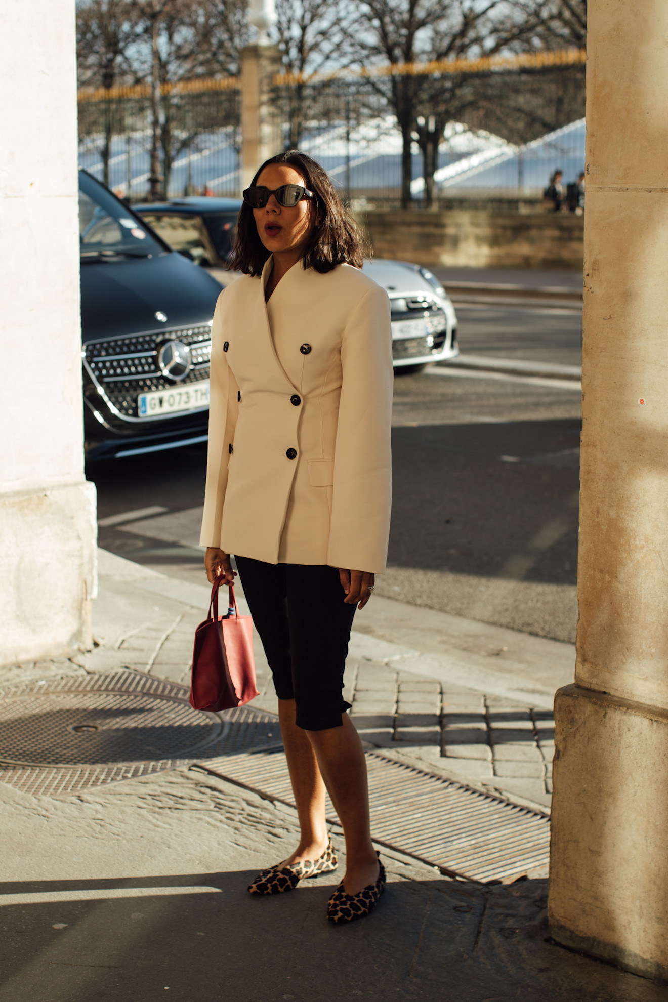 woman wearing a tan fitted blazer, capri pants, and leopard flats in Paris.