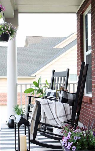 Chic porch scheme with black rocking chairs, mono check cushions, and mono stripe rug.