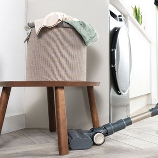 cordless vacuum cleaner underneath laundry basket