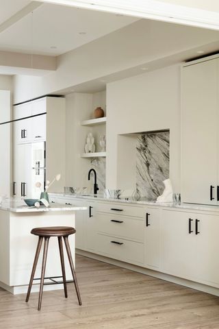 Minimal white kitchen with black handles and backsplash in black and white marble