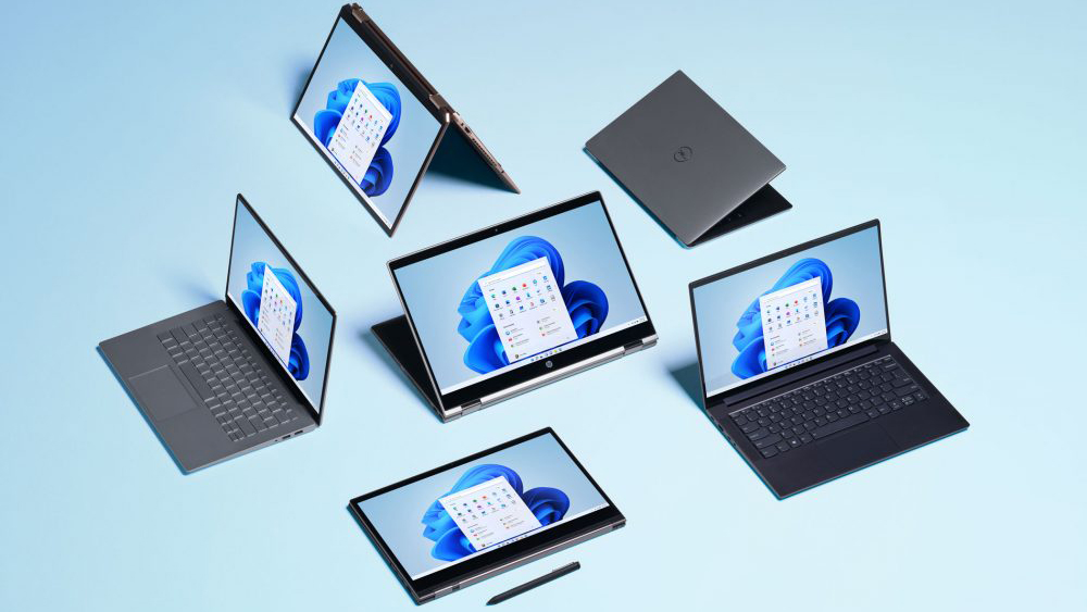 Several Windows 11 devices laid out on a blue surface